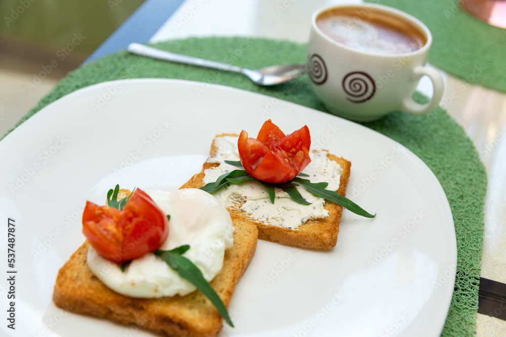 Breakfast with cup of coffee and whole wheat toasted bread with poached egg, tomato, arugula and cheese on white plate. Breakfast with cup of coffee and whole wheat toasted bread with poached egg, tomato, arugula and cheese on white plate.