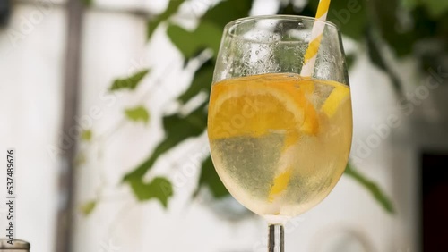 Cold refreshing summer cocktail with citrus, orange and lemon. Female hand mixes a soft drink with a straw and picking it up. Fruit Mojito, Margarita, Tonic water beverage glass juice ice cocktails. (ID: 537489676)