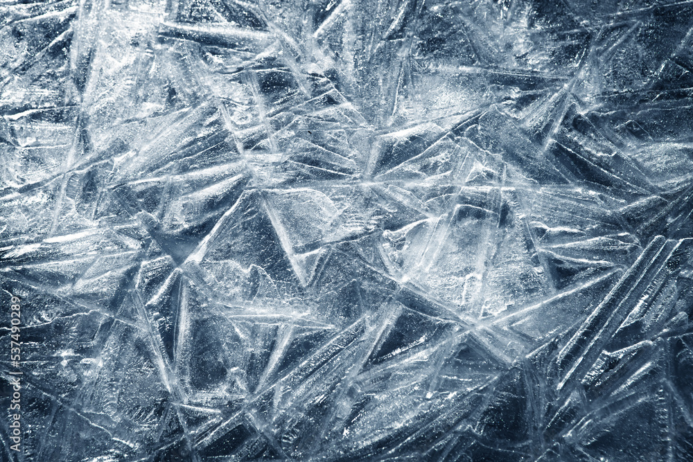 The texture of the ice surface. Winter background, festive background in the form of ice crystals, in natural deep blue color. The texture of the ice surface. Winter background, festive background in the form of ice crystals, in natural deep blue color.