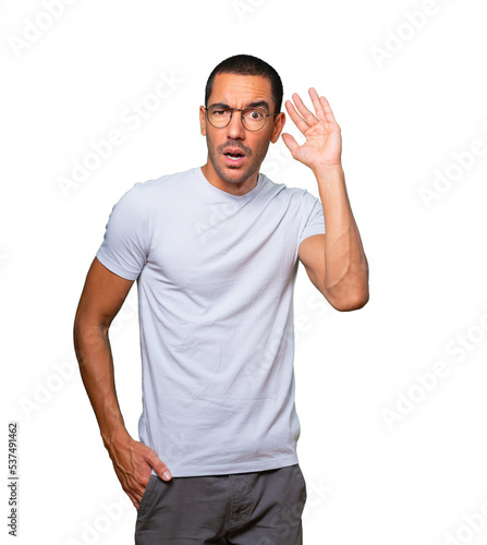 Фотография Concentrated young man making a gesture of trying to hear something