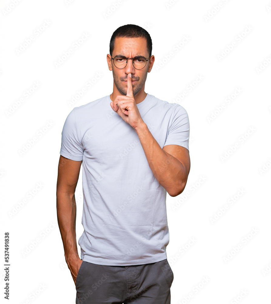 Serious young man asking for silence gesturing with his finger Serious young man asking for silence gesturing with his finger