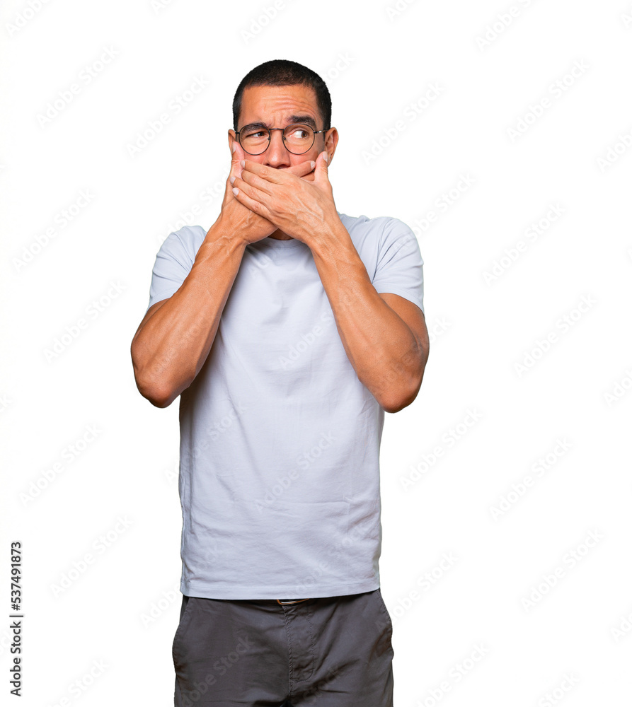 Young man covering his mouth with his hands Young man covering his mouth with his hands