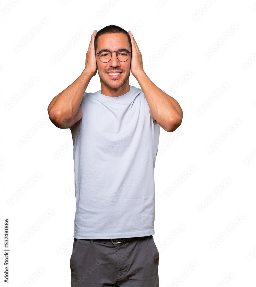 Young man worried about loud noises and covering his ears Young man worried about loud noises and covering his ears