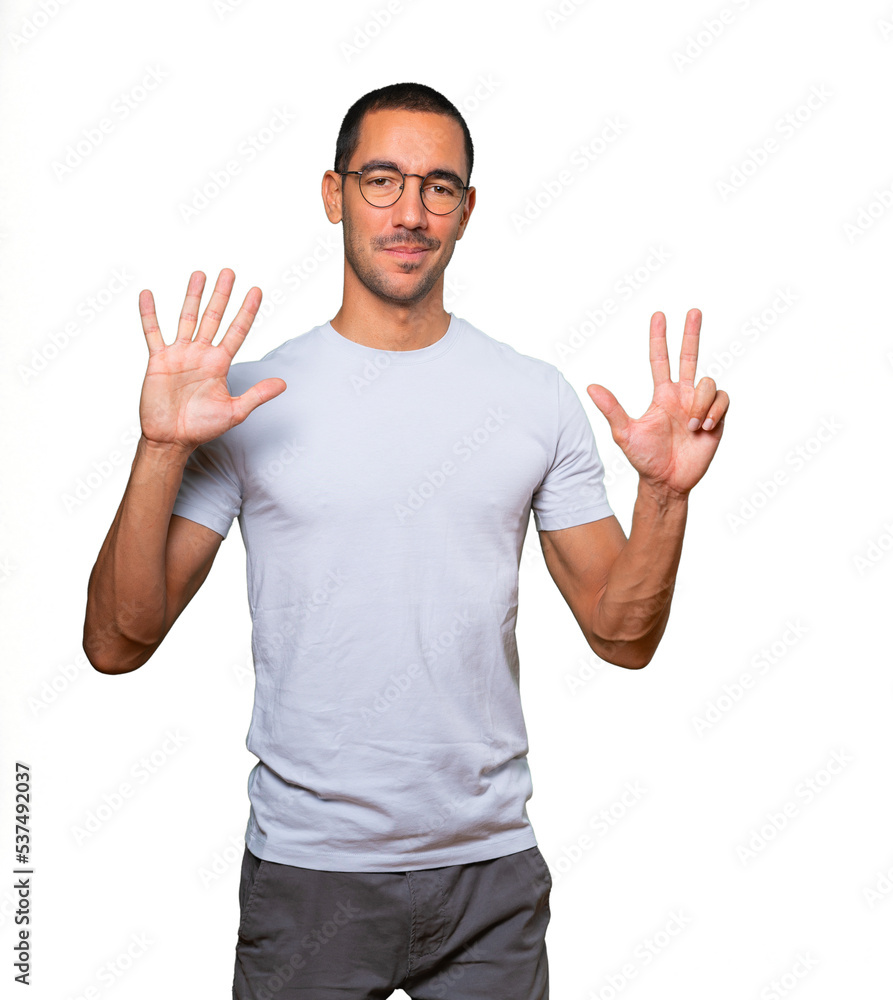 Happy young man doing a number eight gesture with his hands Happy young man doing a number eight gesture with his hands