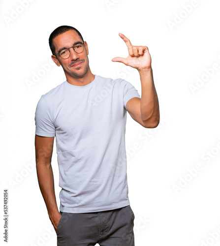 Young man doing a gesture of small size with his hand