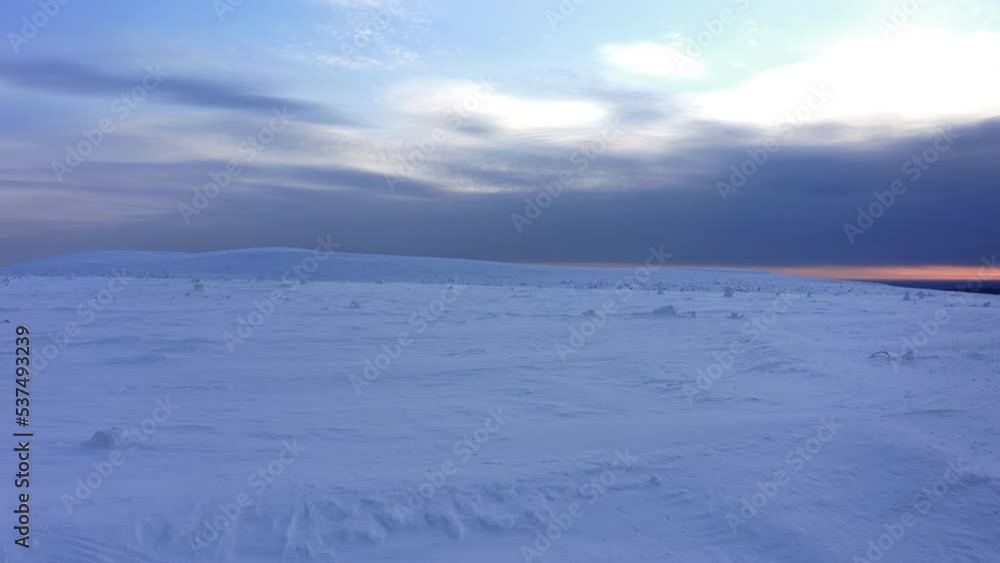 Flight on a copter along the snow-covered and deserted hills of the tundra at dawn in winter Flight on a copter along the snow-covered and deserted hills of the tundra at dawn in winter