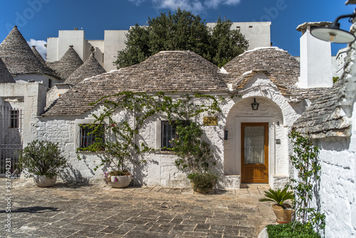 narrow cobblestone streets and round stone trulli houses in Arbelobello. Stone pointed roofs and brick stone whitewashed houses on a sunny day