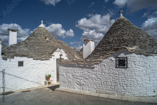 narrow cobblestone streets and round stone trulli houses in Arbelobello. Stone pointed roofs and brick stone whitewashed houses on a sunny day