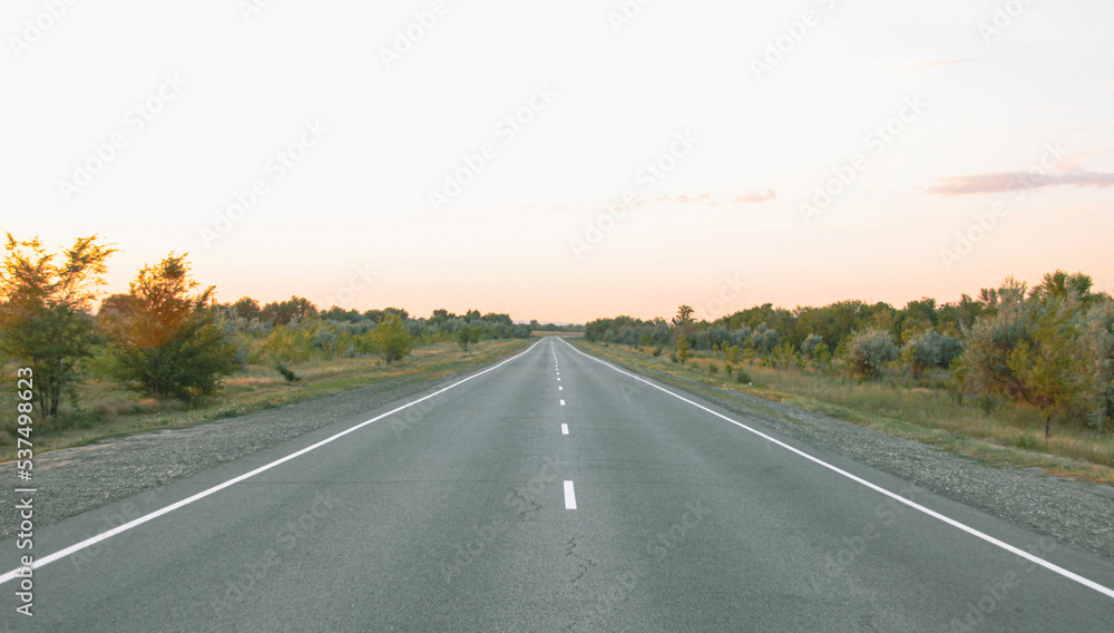 The prospect of a highway during sunset. The highway between the cities. A section of paved road. The prospect of a highway during sunset. The highway between the cities. A section of paved road.