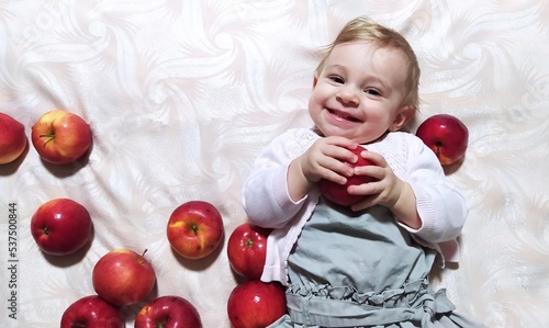 A little girl is holding a red apple