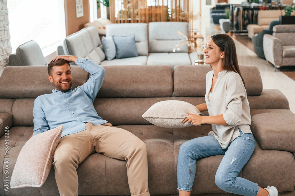 Happy couple choosing the sofa and bed in the store Happy couple choosing the sofa and bed in the store