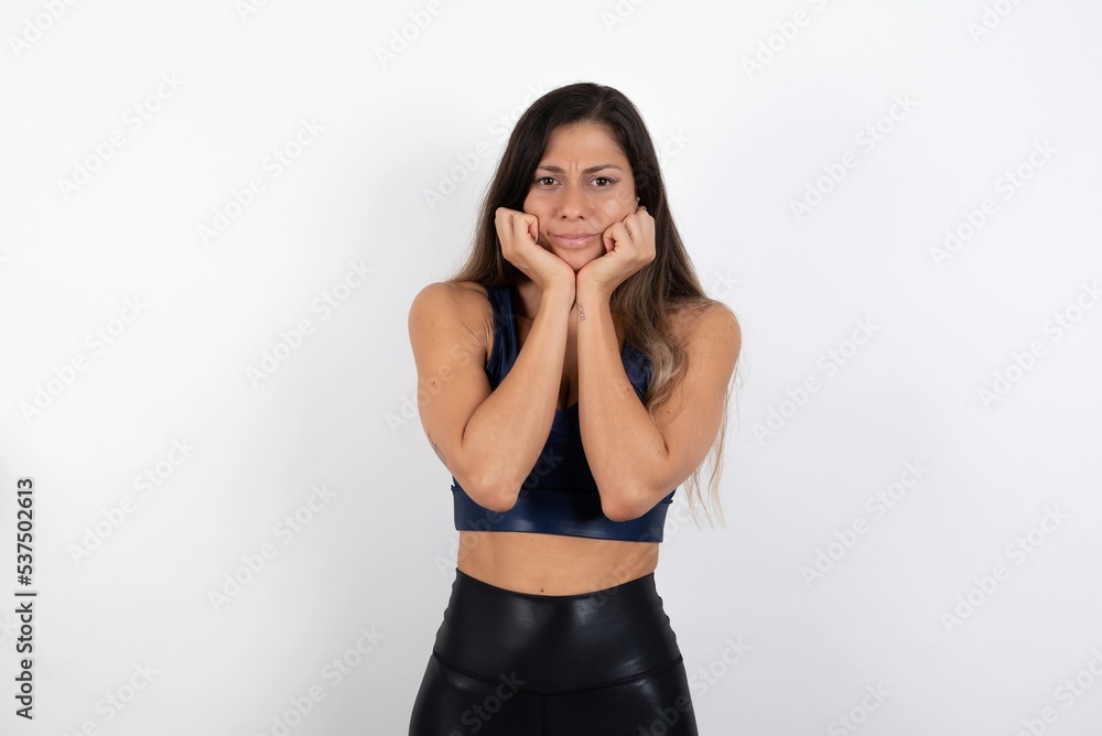 Portrait of sad young beautiful woman wearing sportswear over white background hands face Portrait of sad young beautiful woman wearing sportswear over white background hands face