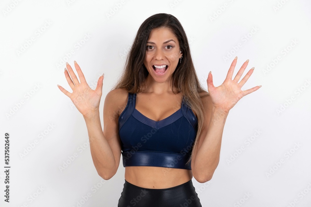 Delighted positive young beautiful woman wearing sportswear over white background opens mouth and arms palms up after having great result Delighted positive young beautiful woman wearing sportswear over white background opens mouth and arms palms up after having great result
