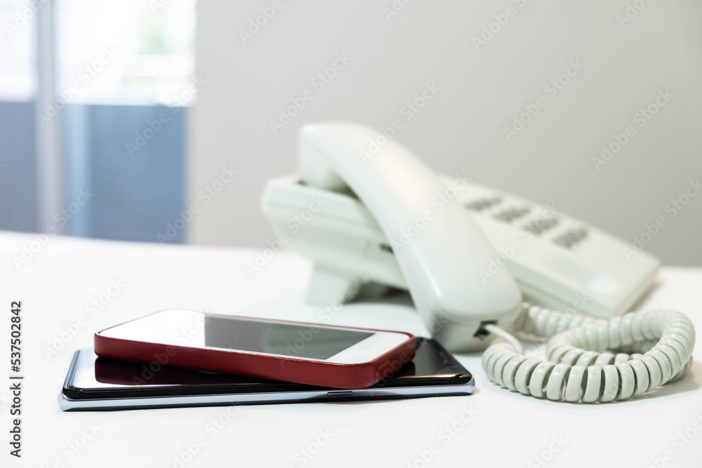 Mobile phone and white color button telephone on white bed sheet Mobile phone and white color button telephone on white bed sheet