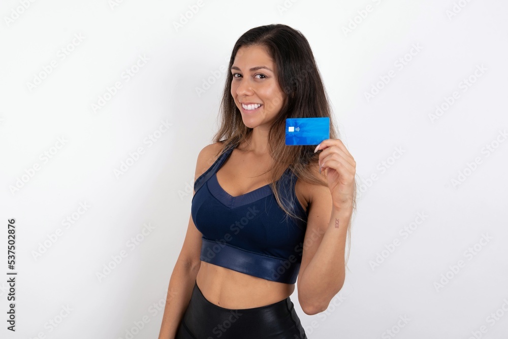 Close up photo of optimistic young beautiful woman wearing sportswear over white background hold card Close up photo of optimistic young beautiful woman wearing sportswear over white background hold card