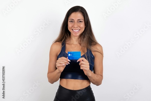 Photo of young beautiful woman wearing sportswear over white background positive smile hold credit card income salary