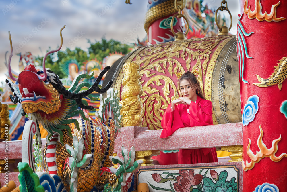 chinese dragon statue. chinese dragon statue in temple. portrait of a woman. person in traditional costume. woman in traditional costume. Beautiful young woman in a bright red dress.