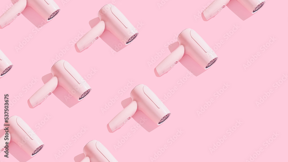 Trendy pattern made of hair dryer on sunny pink background with diagonal copy space. Creative hairdressers wallpaper. Trendy pattern made of hair dryer on sunny pink background with diagonal copy space. Creative hairdressers wallpaper.