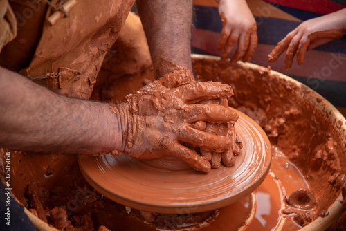 Plano detalle de las manos de un adulto manchadas de barro trabajando y elaborando de manera tradicional objetos de barro cocido en el mercado medieval de Hondarribia en el País Vasco. photo