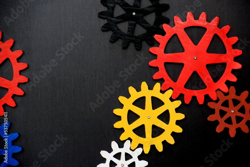 Colorful wooden gears on a black background. Space for text. A toy for children's development