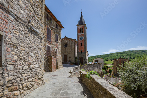 Walking narrow stone streets of old small mountain town. View of ancient Santa Maria Assunta church. Ambra, Bucine, Arezzo, Tuscany, Italy photo