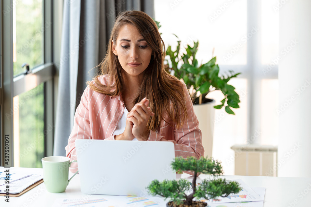 Focused business woman using laptop at home, looking at screen, chatting, reading or writing email, sitting on couch, female student doing homework, working on research project online Focused business woman using laptop at home, looking at screen, chatting, reading or writing email, sitting on couch, female student doing homework, working on research project online