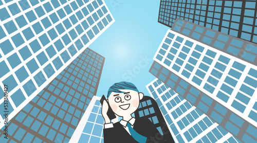 高層ビルをバックに電話をかける男性