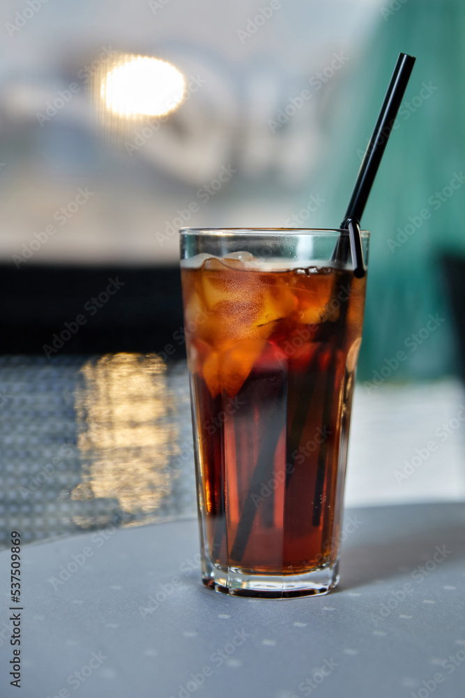 Alcoholic cocktail with cola, ice and lemon on the cafe table Alcoholic cocktail with cola, ice and lemon on the cafe table