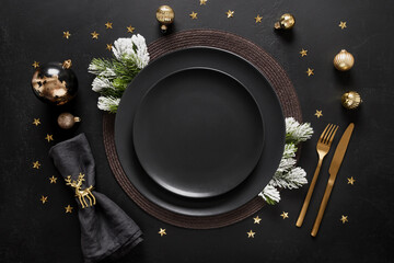 New Year black table setting with elegant golden decorations on black table for festive dinner and party. View from above. Copy space.