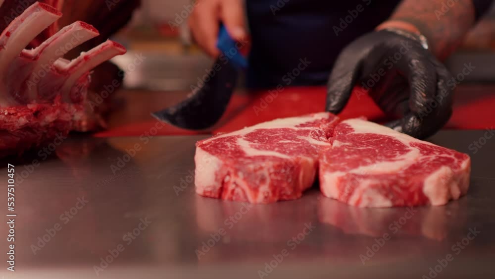 Chef hands making a heart shape form raw fresh beef meat ribeye. Juicy fresh meat steak on board with different meat goods around.