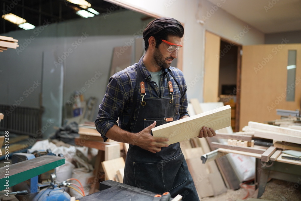 Contemporary Carpenter Working, Portrait of modern carpenter making wood furniture while working in joinery lit by sunlight with factory background on small business concept, copy space Contemporary Carpenter Working, Portrait of modern carpenter making wood furniture while working in joinery lit by sunlight with factory background on small business concept, copy space