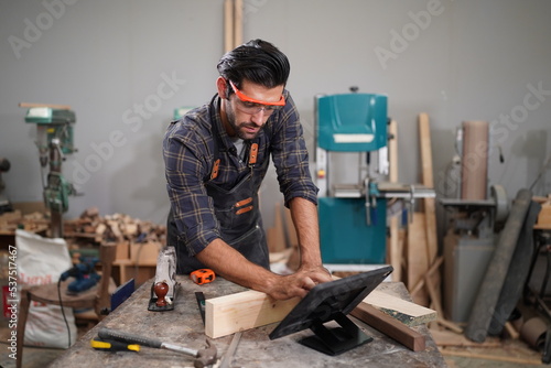 Contemporary Carpenter Working, Portrait of modern carpenter making wood furniture while working in joinery lit by sunlight with factory background on small business concept, copy space