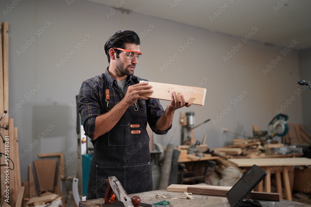 Contemporary Carpenter Working, Portrait of modern carpenter making wood furniture while working in joinery lit by sunlight with factory background on small business concept, copy space Contemporary Carpenter Working, Portrait of modern carpenter making wood furniture while working in joinery lit by sunlight with factory background on small business concept, copy space
