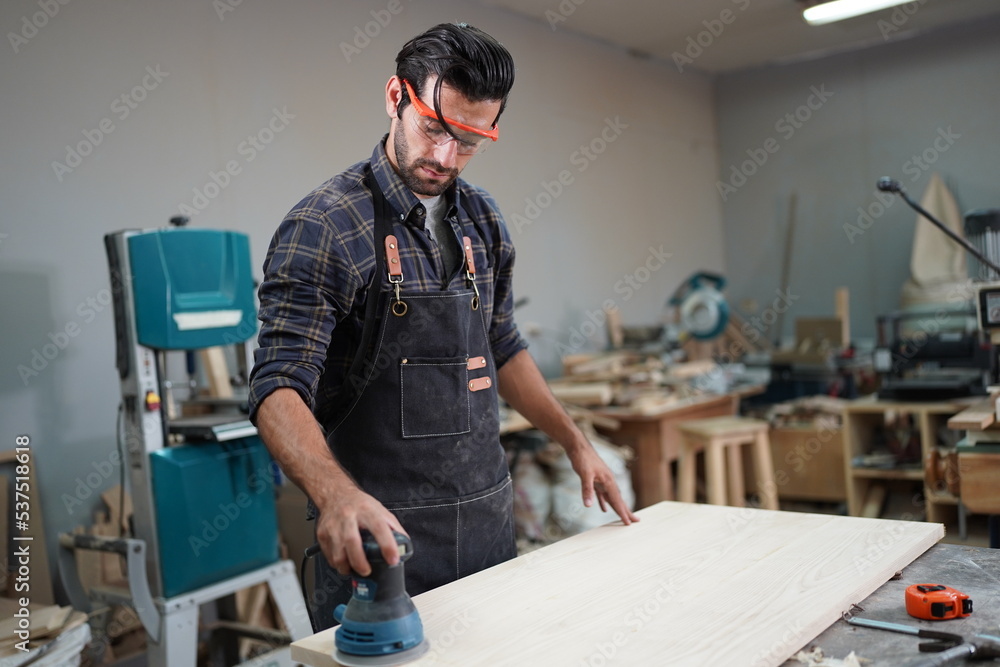 Contemporary Carpenter Working, Portrait of modern carpenter making wood furniture while working in joinery lit by sunlight with factory background on small business concept, copy space Contemporary Carpenter Working, Portrait of modern carpenter making wood furniture while working in joinery lit by sunlight with factory background on small business concept, copy space