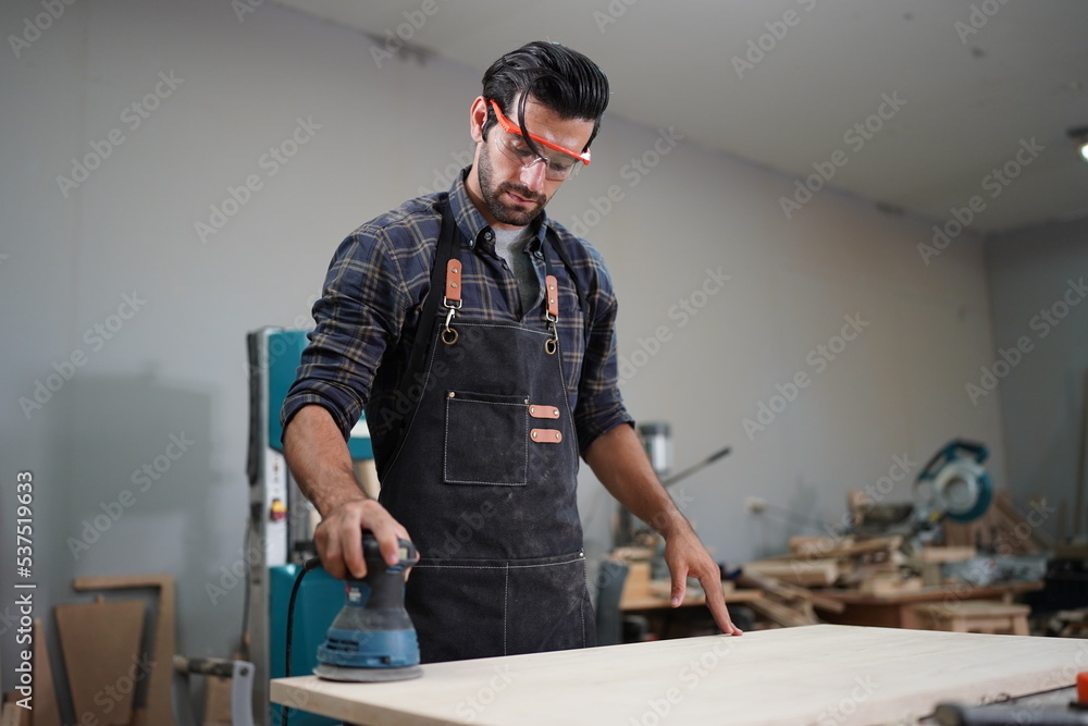 Contemporary Carpenter Working, Portrait of modern carpenter making wood furniture while working in joinery lit by sunlight with factory background on small business concept, copy space Contemporary Carpenter Working, Portrait of modern carpenter making wood furniture while working in joinery lit by sunlight with factory background on small business concept, copy space