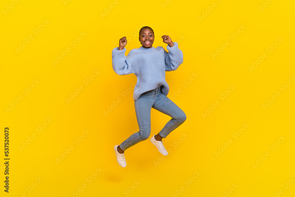 Full size photo of optimistic young nice lady jump wear blue sweater jeans sneakers isolated on grey color background