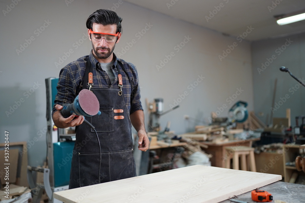 Contemporary Carpenter Working, Portrait of modern carpenter making wood furniture while working in joinery lit by sunlight with factory background on small business concept, copy space Contemporary Carpenter Working, Portrait of modern carpenter making wood furniture while working in joinery lit by sunlight with factory background on small business concept, copy space