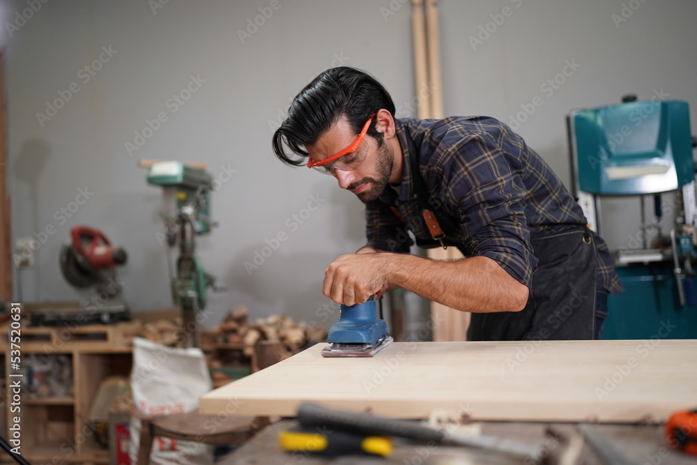 Contemporary Carpenter Working, Portrait of modern carpenter making wood furniture while working in joinery lit by sunlight with factory background on small business concept, copy space Contemporary Carpenter Working, Portrait of modern carpenter making wood furniture while working in joinery lit by sunlight with factory background on small business concept, copy space