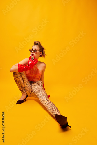 Weird people concept. Creative portrait of young girl in avant-garde style image isolated over bright yellow background. Vivid style, queer, art, fashion