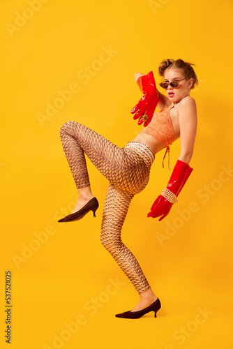 Weird people concept. Creative portrait of young girl in avant-garde style image isolated over bright yellow background. Vivid style, queer, art, fashion photo