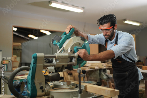 Contemporary Carpenter Working, Portrait of modern carpenter making wood furniture while working in joinery lit by sunlight with factory background on small business concept, copy space