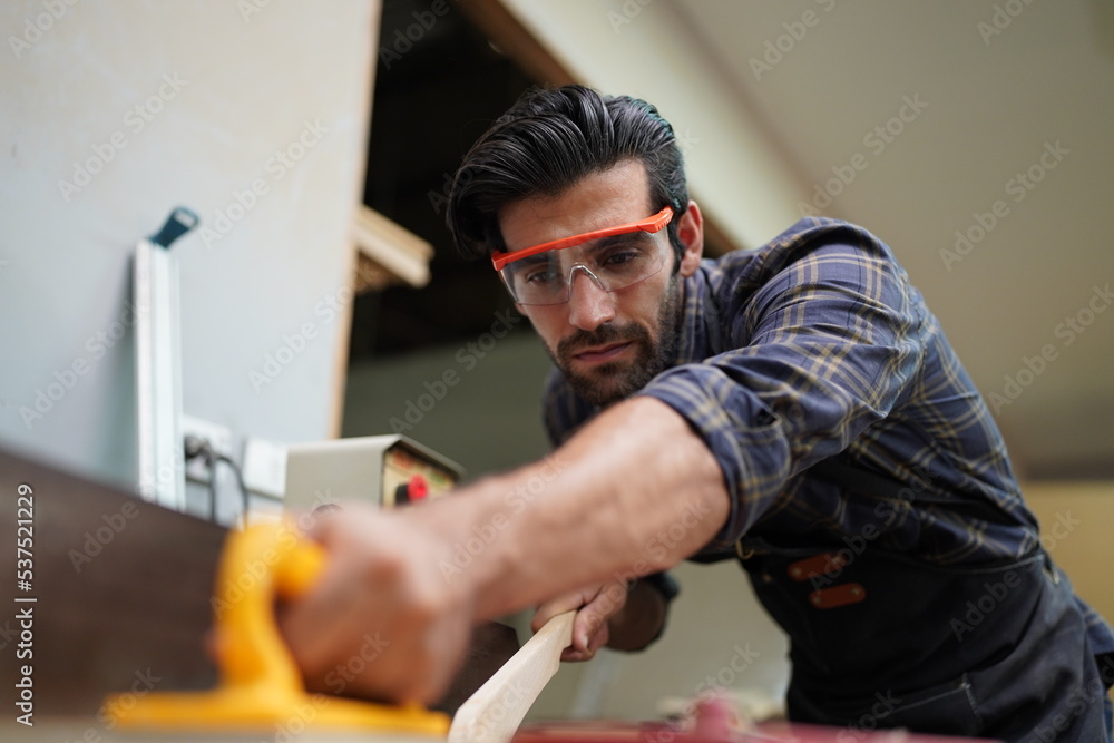 Contemporary Carpenter Working, Portrait of modern carpenter making wood furniture while working in joinery lit by sunlight with factory background on small business concept, copy space Contemporary Carpenter Working, Portrait of modern carpenter making wood furniture while working in joinery lit by sunlight with factory background on small business concept, copy space