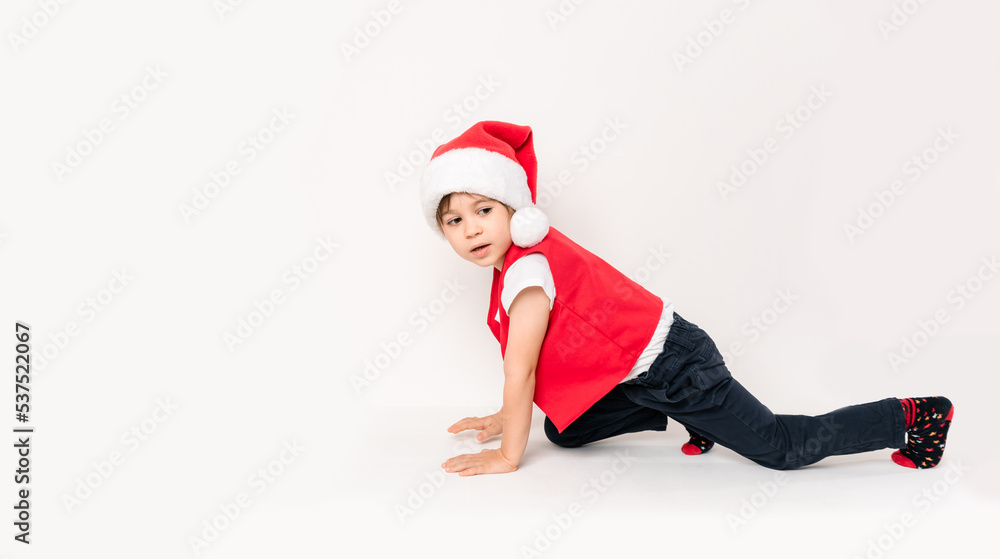Portrait of happy child standing on the start in Santa Claus hat isolated on white background. 5 year European boy starting run a marathon. Banner. Copy space. Concept of New Year gift certificate Portrait of happy child standing on the start in Santa Claus hat isolated on white background. 5 year European boy starting run a marathon. Banner. Copy space. Concept of New Year gift certificate