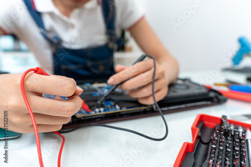 Asian woman using a power meter to check laptop board to repair or replace. Selective focus her hand.