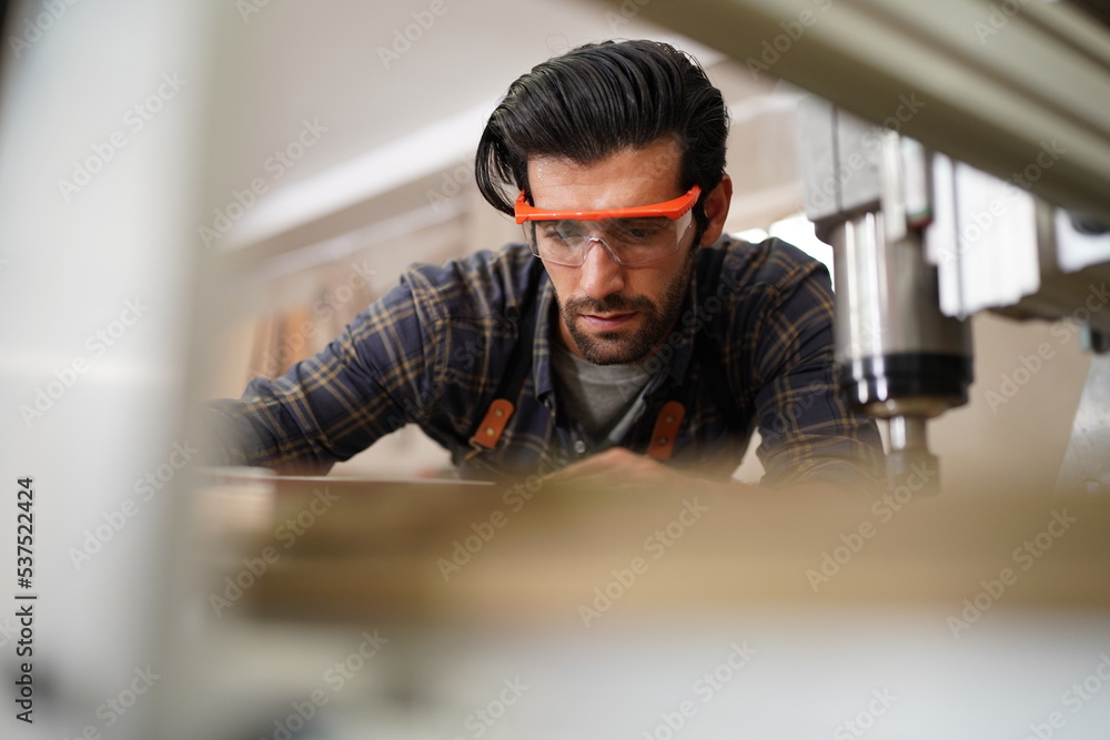 Contemporary Carpenter Working, Portrait of modern carpenter making wood furniture while working in joinery lit by sunlight with factory background on small business concept, copy space Contemporary Carpenter Working, Portrait of modern carpenter making wood furniture while working in joinery lit by sunlight with factory background on small business concept, copy space