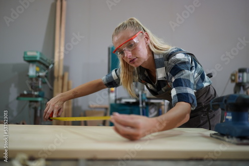 Contemporary Carpenter Working, Portrait of modern carpenter making wood furniture while working in joinery lit by sunlight with factory background on small business concept, copy space © FotoArtist