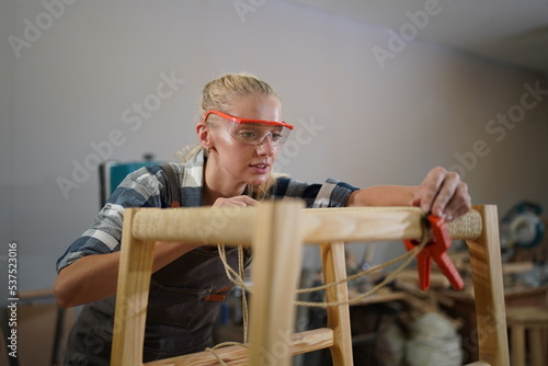 Contemporary Carpenter Working, Portrait of modern carpenter making wood furniture while working in joinery lit by sunlight with factory background on small business concept, copy space