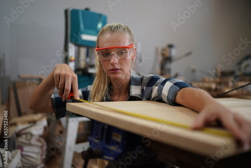 Contemporary Carpenter Working, Portrait of modern carpenter making wood furniture while working in joinery lit by sunlight with factory background on small business concept, copy space © FotoArtist