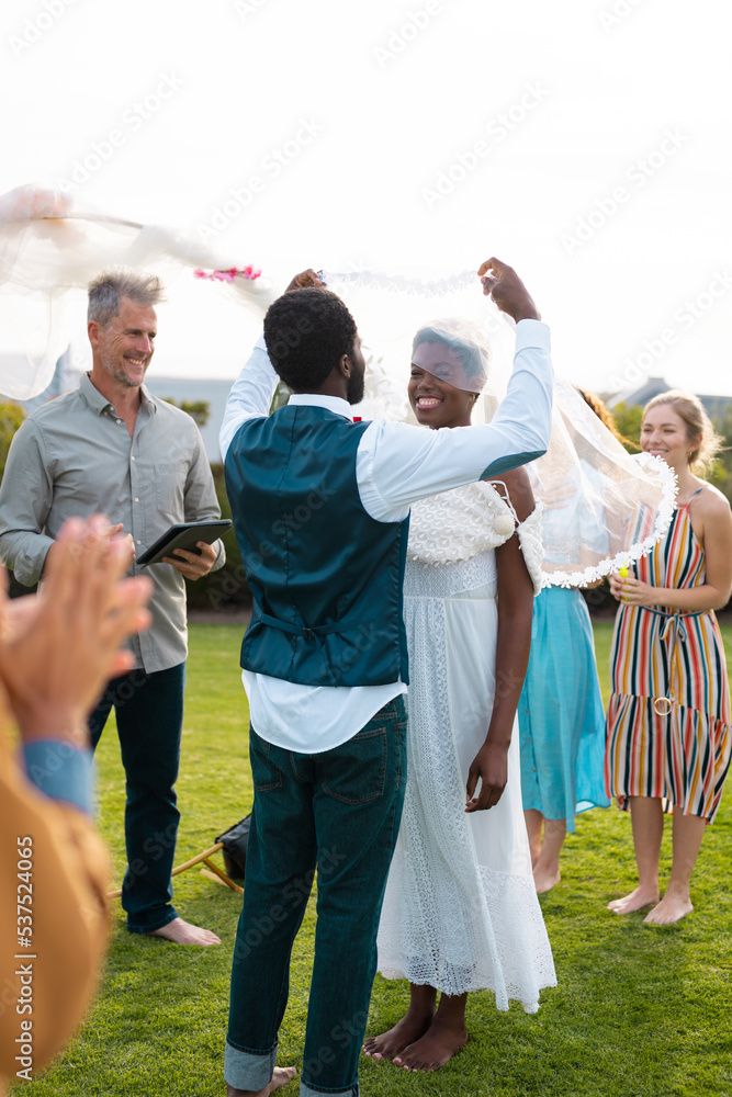 Happy african american couple holding veil and smiling during wedding Happy african american couple holding veil and smiling during wedding