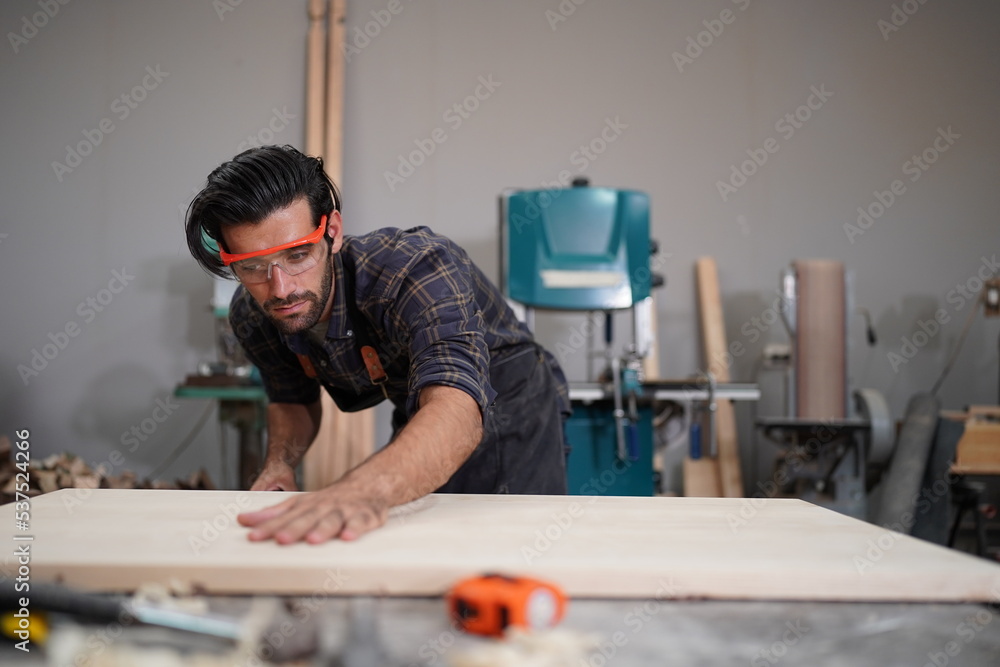 Contemporary Carpenter Working, Portrait of modern carpenter making wood furniture while working in joinery lit by sunlight with factory background on small business concept, copy space Contemporary Carpenter Working, Portrait of modern carpenter making wood furniture while working in joinery lit by sunlight with factory background on small business concept, copy space